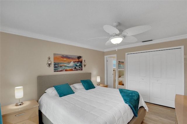 bedroom with light wood-style flooring, visible vents, a ceiling fan, a closet, and crown molding