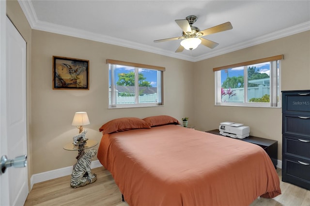 bedroom featuring baseboards, crown molding, multiple windows, and light wood-style floors