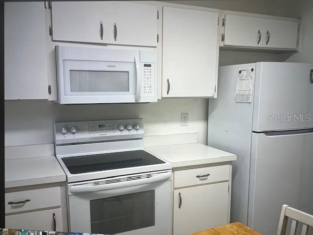 kitchen with white appliances, light countertops, and white cabinets