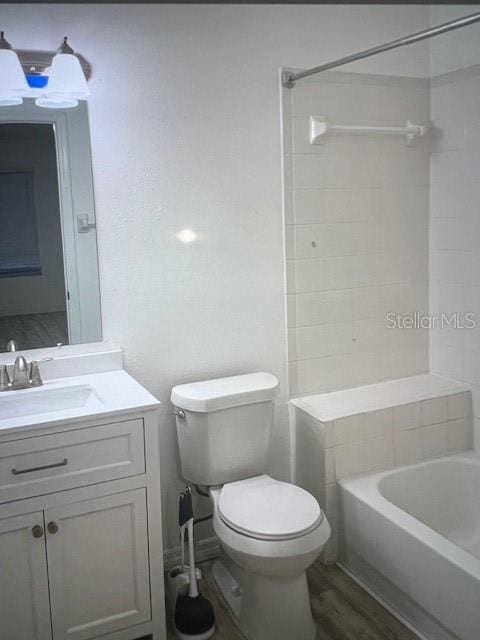 full bath with toilet, vanity, wood finished floors, and bathing tub / shower combination