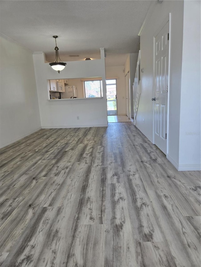 unfurnished living room with a textured ceiling, crown molding, stairs, and wood finished floors