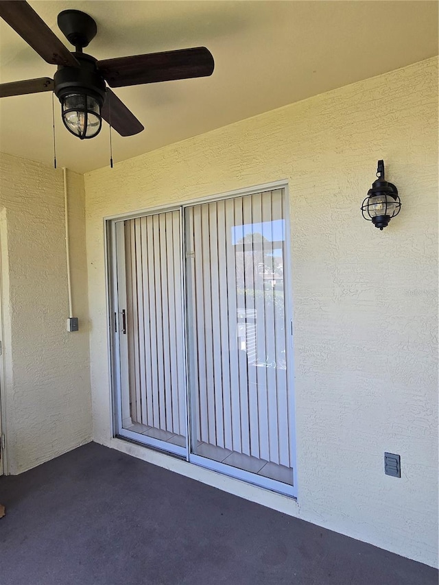 property entrance featuring ceiling fan and stucco siding