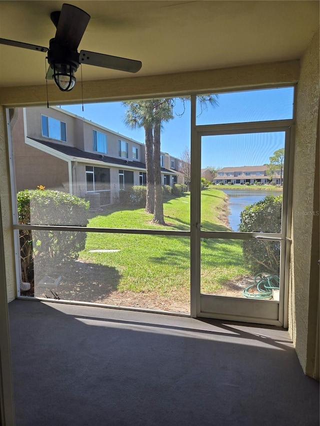 unfurnished sunroom featuring ceiling fan and a water view