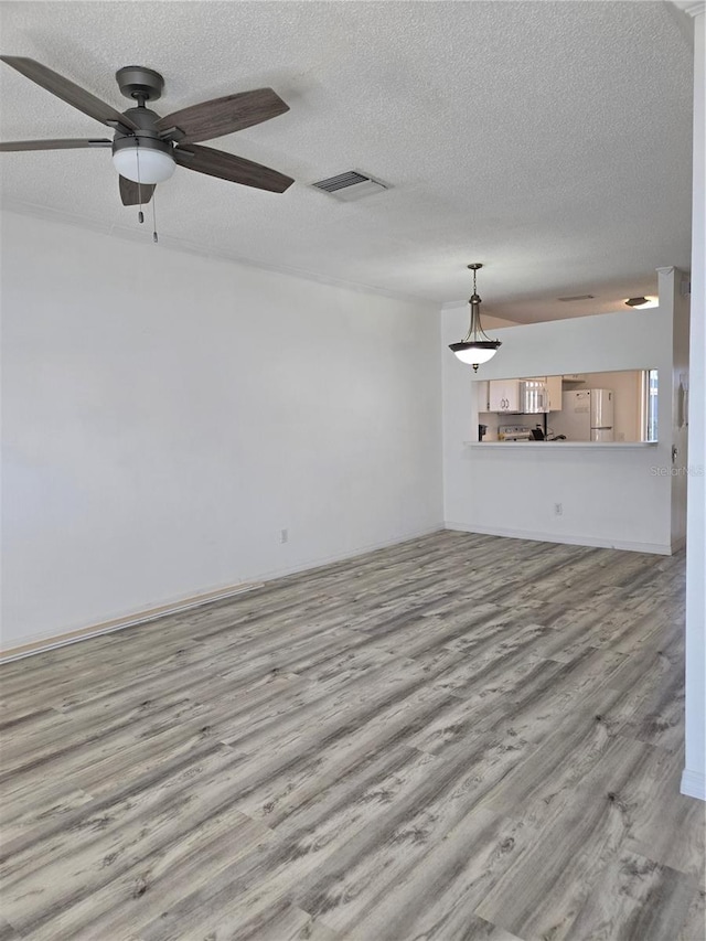 unfurnished living room featuring a ceiling fan, visible vents, a textured ceiling, and wood finished floors