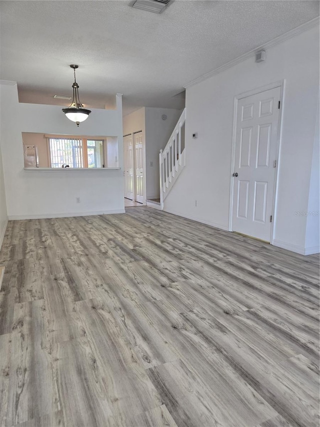 unfurnished living room with stairs, a textured ceiling, and wood finished floors