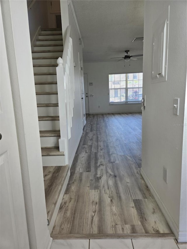 interior space with baseboards, stairway, a textured ceiling, and wood finished floors