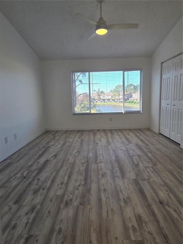 interior space featuring lofted ceiling, a closet, a ceiling fan, a textured ceiling, and wood finished floors