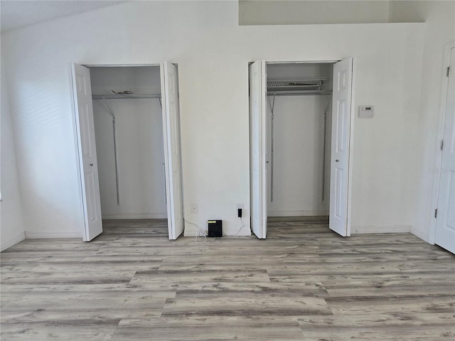 unfurnished bedroom featuring multiple closets and wood finished floors