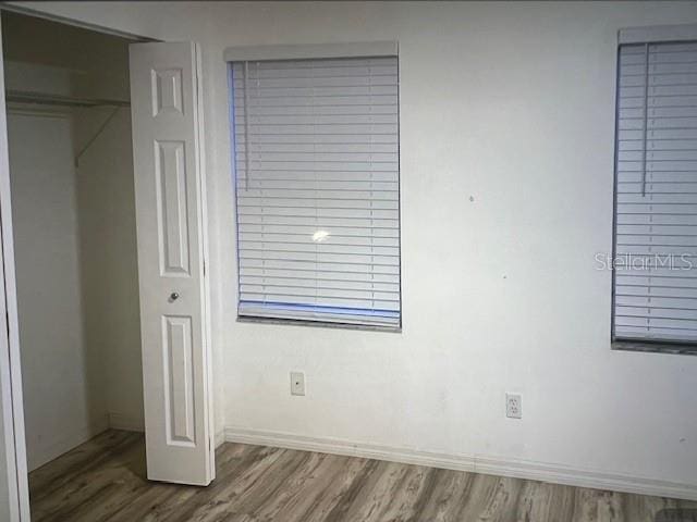 unfurnished bedroom featuring a closet, baseboards, and wood finished floors