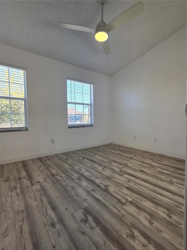 empty room with ceiling fan, a textured ceiling, baseboards, and wood finished floors