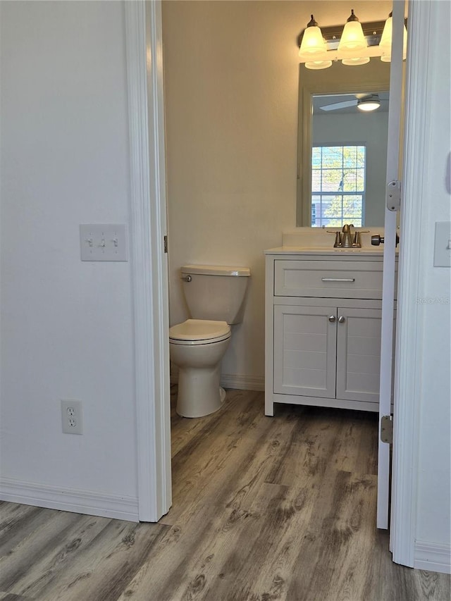 bathroom with baseboards, vanity, toilet, and wood finished floors