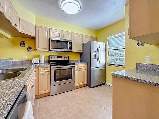 kitchen with light tile patterned floors, stainless steel appliances, a textured ceiling, and a textured wall