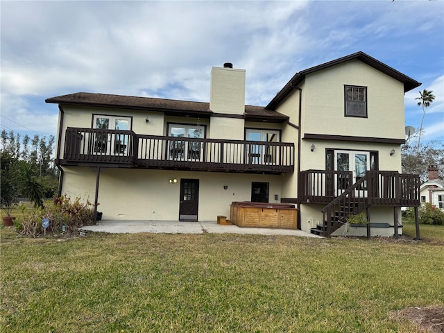 rear view of house featuring a chimney, stucco siding, a lawn, a hot tub, and a patio area