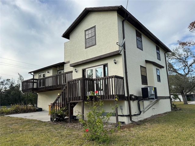 back of house featuring a lawn, stairway, a wooden deck, a patio area, and stucco siding