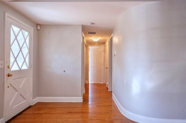 hallway featuring visible vents, light wood-style flooring, and baseboards