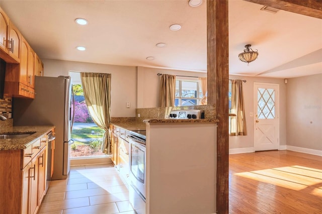 kitchen featuring a sink, stone countertops, stainless steel dishwasher, and light wood-style flooring