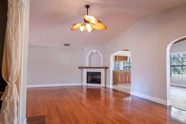 unfurnished living room with visible vents, a fireplace, lofted ceiling, and wood finished floors