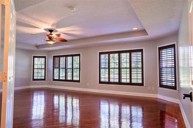 spare room with a tray ceiling, baseboards, and a textured ceiling