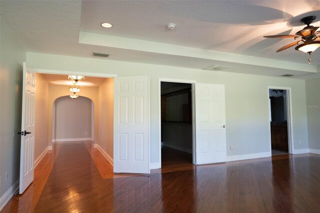 spare room with a ceiling fan, a textured ceiling, hardwood / wood-style floors, arched walkways, and baseboards