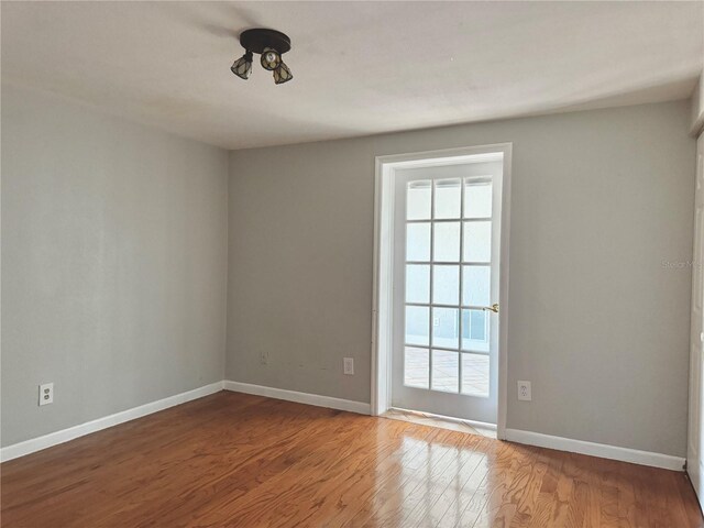 spare room featuring baseboards and wood finished floors