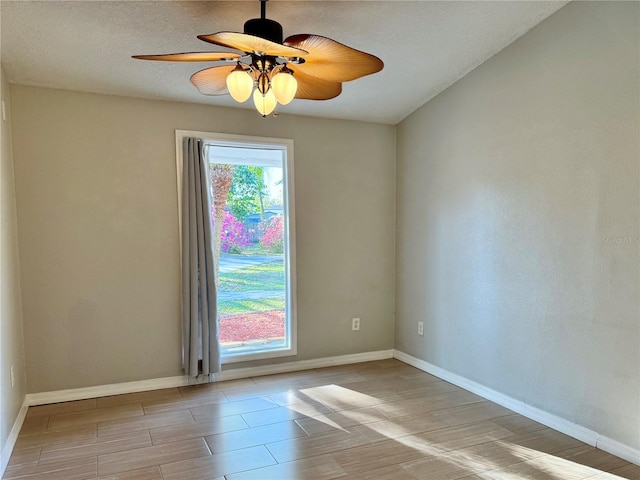 empty room featuring a healthy amount of sunlight, baseboards, and ceiling fan