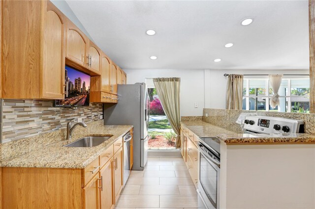 kitchen with backsplash, light stone countertops, dishwasher, electric range, and a sink