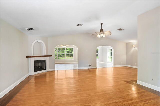 unfurnished living room featuring visible vents, lofted ceiling, wood finished floors, and a fireplace