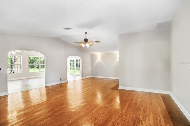 spare room with arched walkways, visible vents, ceiling fan, and wood finished floors