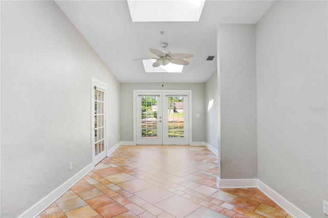 interior space with french doors, baseboards, a skylight, and a textured wall