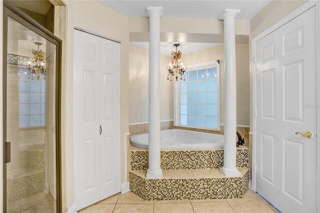 bathroom featuring a garden tub, ornate columns, an inviting chandelier, a shower stall, and tile patterned floors