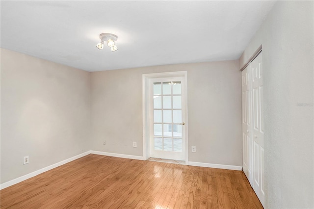 empty room featuring baseboards and light wood finished floors