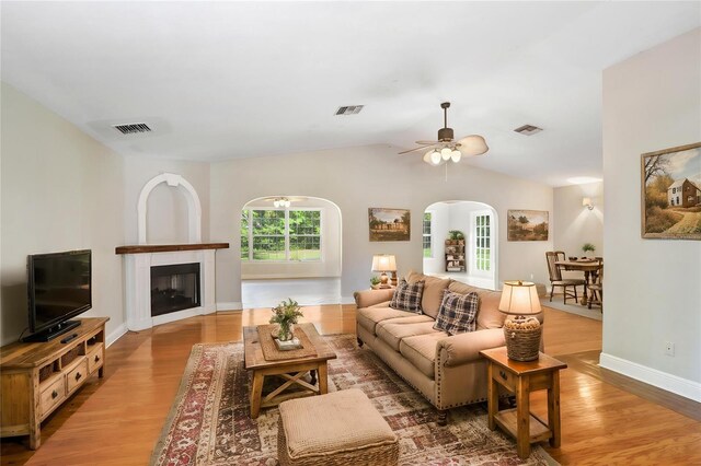 19531 Deer Lake Rd, Lutz, FL 33548 - living area featuring wood finished floors, ceiling fan, arched walkways, a fireplace, and vaulted ceiling