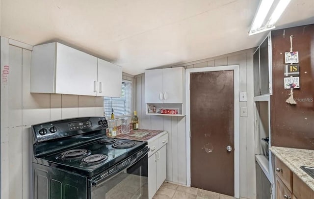 kitchen with light stone counters, white cabinetry, and electric range