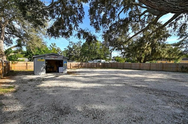 view of yard featuring a fenced backyard, a storage unit, and an outbuilding