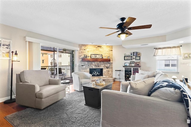 living room with a textured ceiling, a fireplace, wood finished floors, and a wealth of natural light