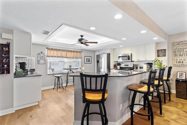 kitchen featuring appliances with stainless steel finishes, light wood-type flooring, a raised ceiling, and visible vents