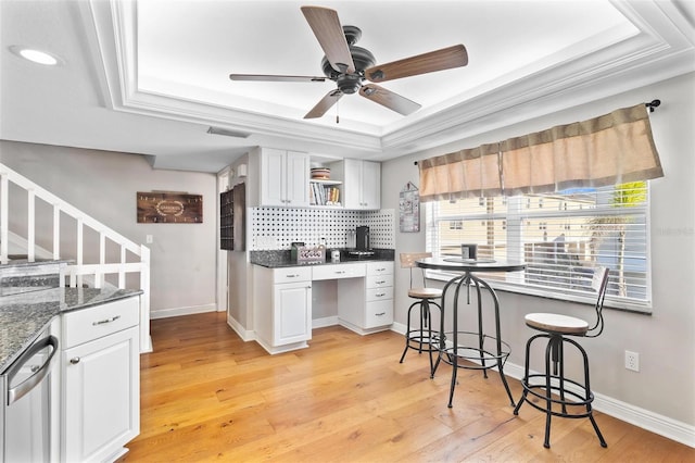 kitchen featuring light wood-type flooring, white cabinetry, a tray ceiling, and ornamental molding