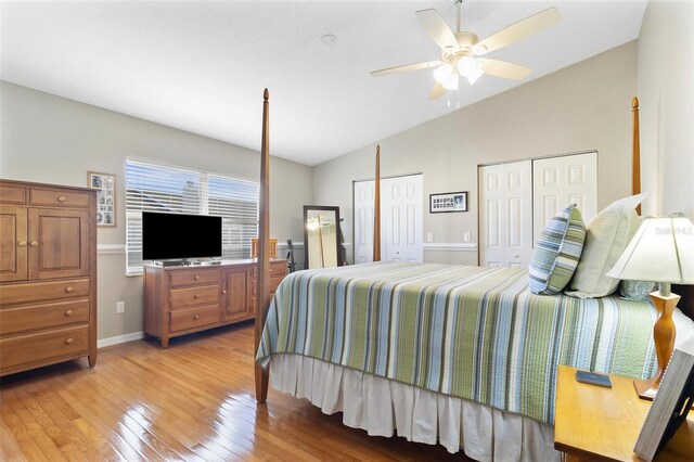 bedroom featuring multiple closets, light wood-style floors, a ceiling fan, vaulted ceiling, and baseboards