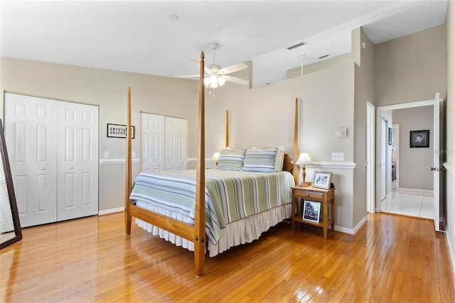 bedroom featuring baseboards, light wood-style flooring, visible vents, and multiple closets