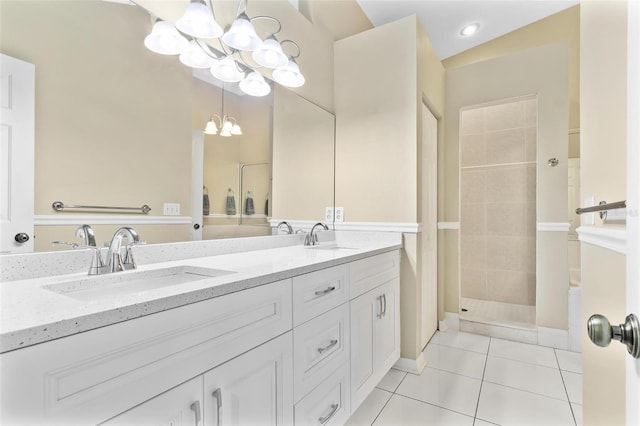 bathroom featuring an inviting chandelier, tile patterned flooring, a tile shower, and a sink