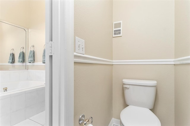 bathroom with toilet, a garden tub, and visible vents