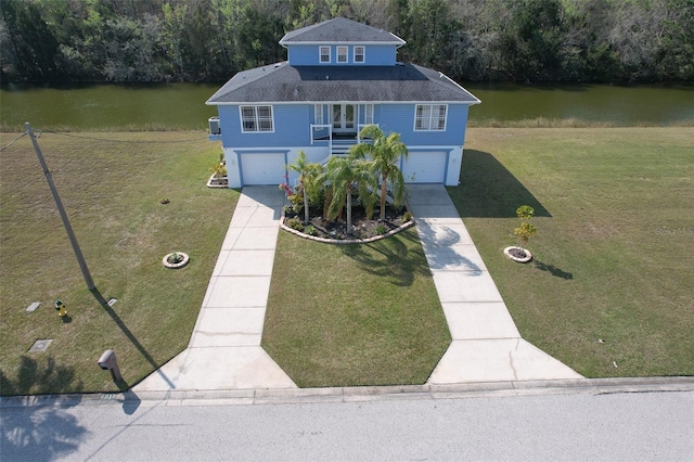 view of front facade with a water view, a front lawn, and driveway