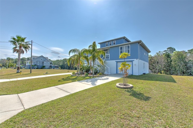 raised beach house with stairs, a front lawn, an attached garage, and driveway