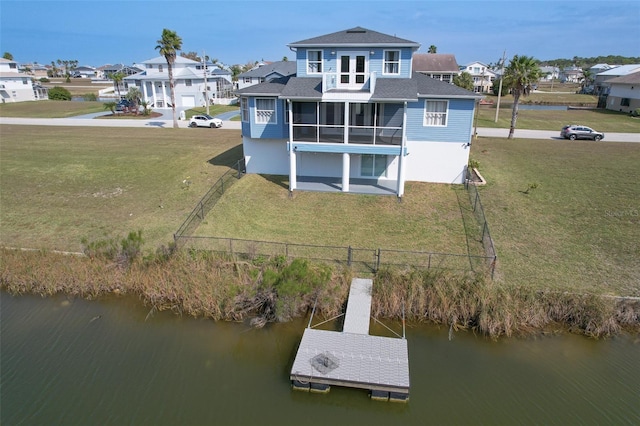 back of house featuring a residential view, a lawn, a water view, and a sunroom