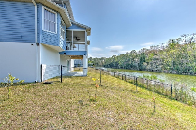 view of yard featuring ceiling fan, a water view, and a fenced backyard