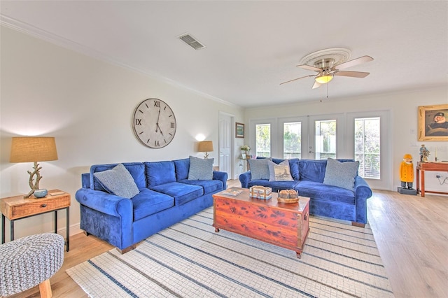 living area with crown molding, visible vents, and light wood finished floors