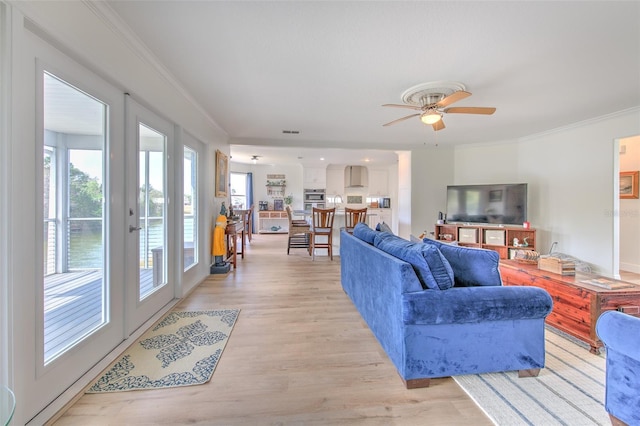 living room featuring visible vents, french doors, crown molding, light wood finished floors, and ceiling fan