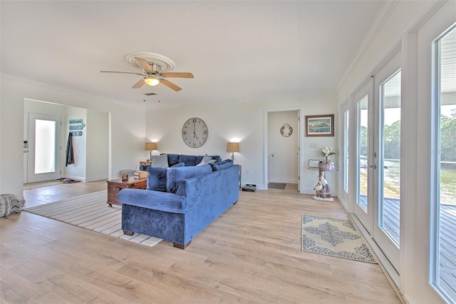 living room with light wood-style flooring, a ceiling fan, crown molding, and baseboards