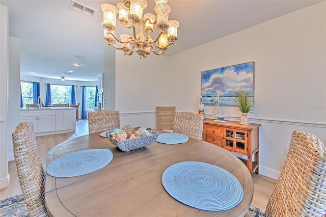 dining room featuring light wood-style flooring, a notable chandelier, and visible vents