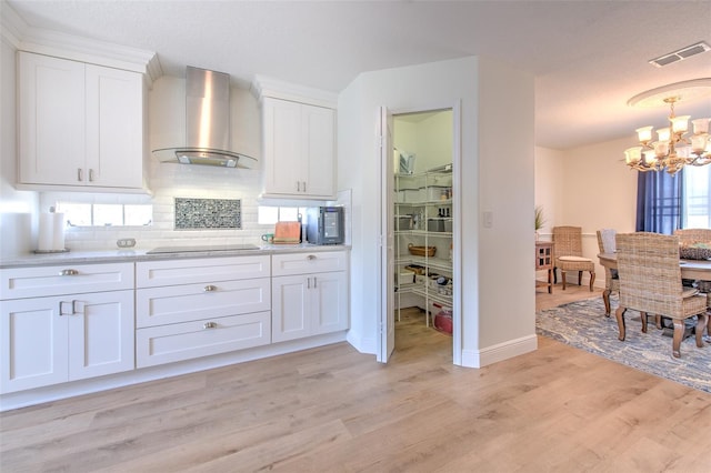 kitchen featuring visible vents, wall chimney range hood, light wood-style floors, white cabinetry, and black electric cooktop